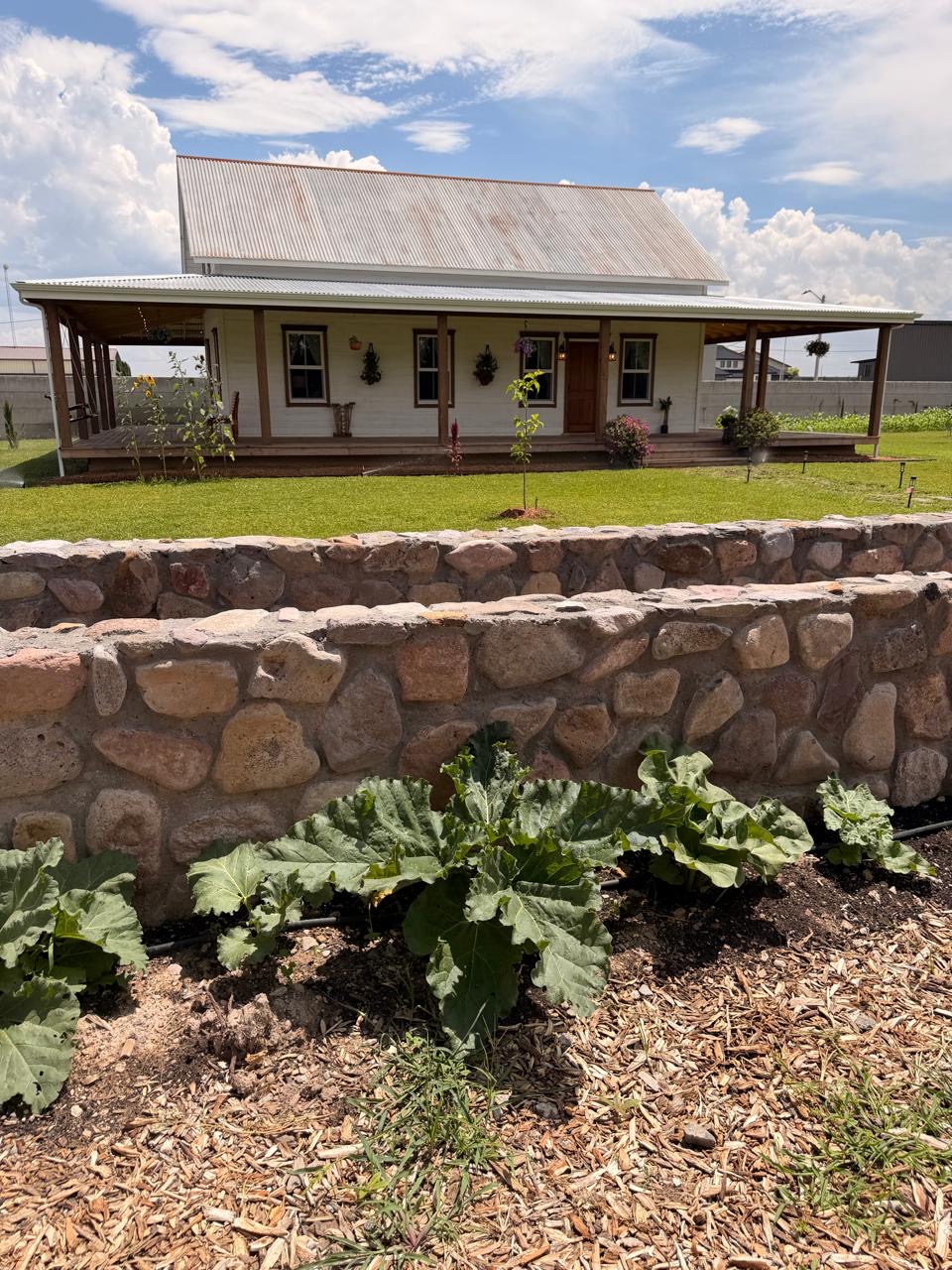 Wraparound porch above the hand-laid stone garden wall