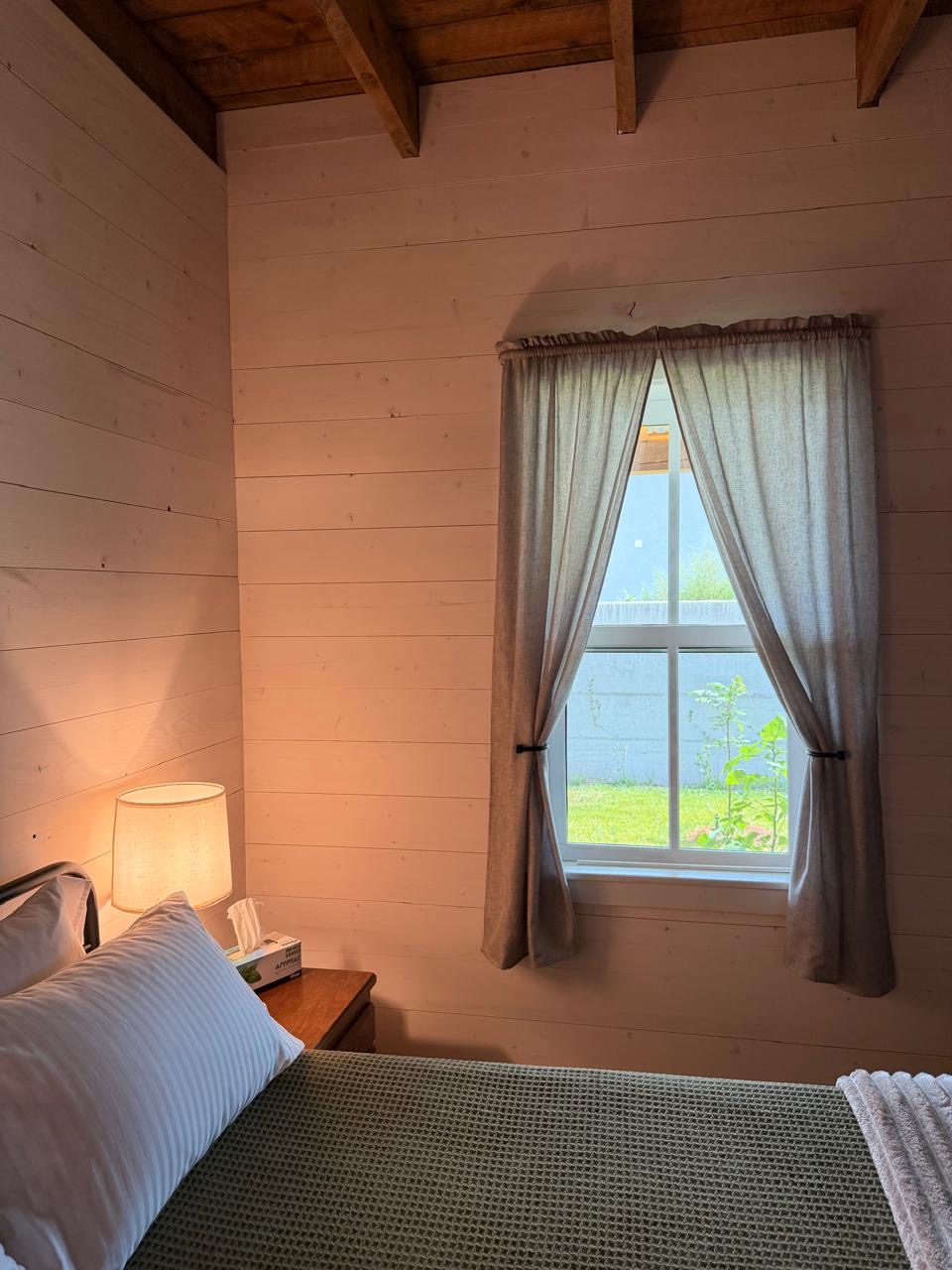 Cozy guest bedroom with linen curtains and a bedside lamp