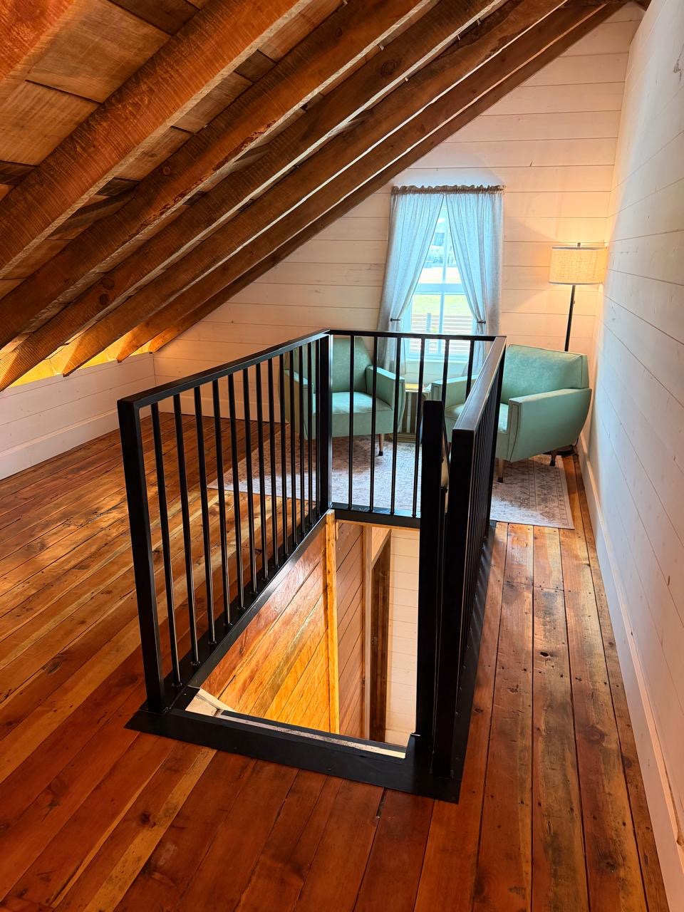 Loft landing under a vaulted reclaimed-timber ceiling with two green armchairs