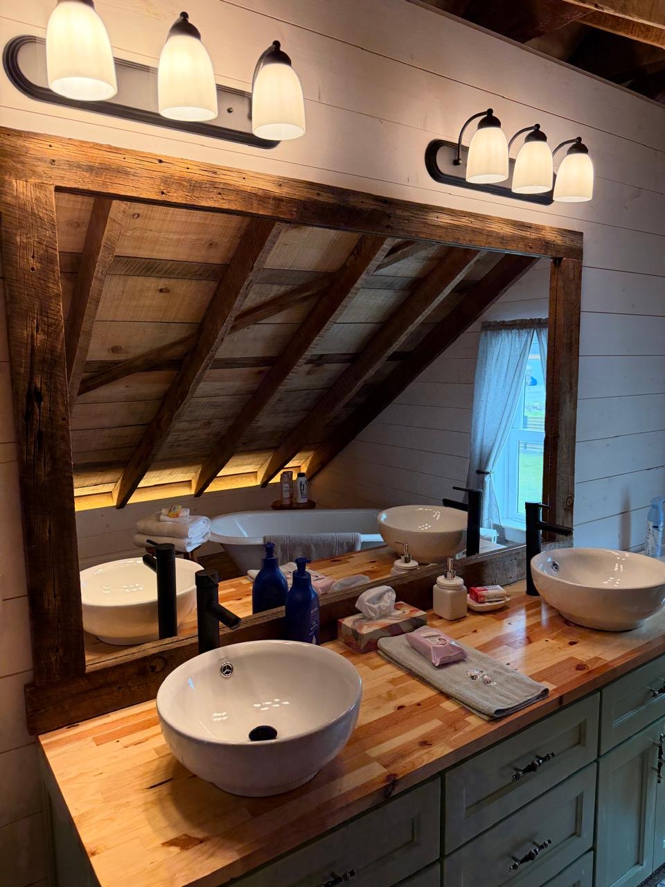 Bathroom vanity with double vessel sinks and a large reclaimed-wood mirror
