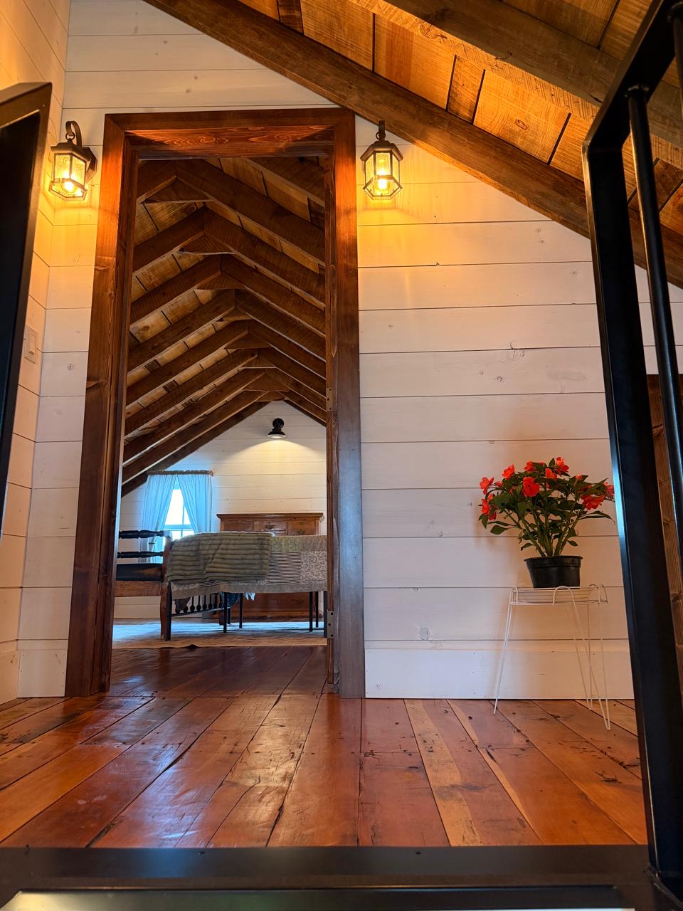 Upstairs hallway with a doorway into a beamed bedroom and a flowering plant